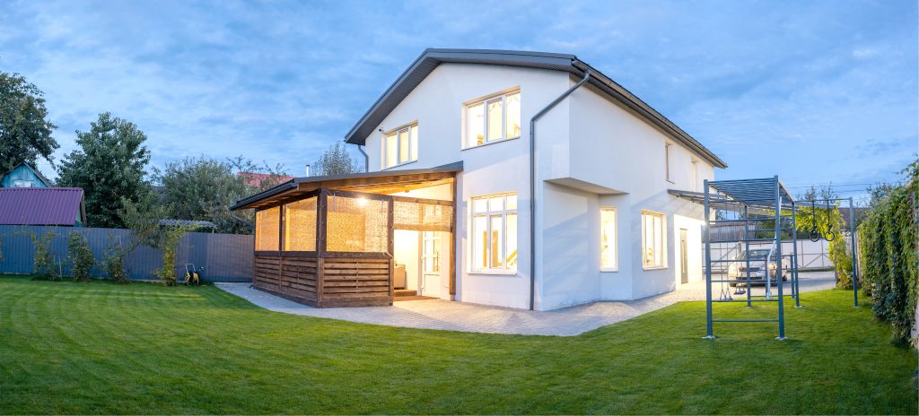 exterior-view-modern-white-house-with-courtyard-patio-area-green-grass-lawn-garden-car-evening